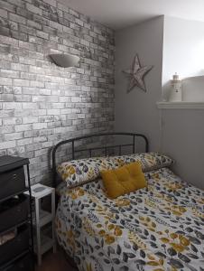 um quarto com uma cama com almofadas amarelas e uma parede de tijolos em Berwick upon Tweed flat em Berwick-Upon-Tweed