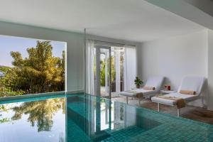 a house with a swimming pool and a living room at Casas Brancas Boutique Hotel & Spa in Búzios