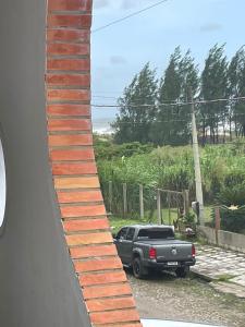 una pared de ladrillo con un camión estacionado en una entrada en Residencial Brila Mar, en Capão da Canoa