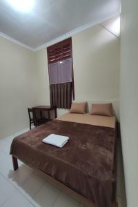ein Schlafzimmer mit einem Bett, einem Stuhl und einem Fenster in der Unterkunft OYO 93173 Khazanah Room Syariah in Yogyakarta