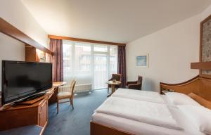 a hotel room with a bed and a flat screen tv at Gästehaus Pergola in Rotenburg an der Fulda