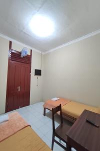 ジョグジャカルタにあるOYO 93173 Khazanah Room Syariahのベッド2台、テーブル、ドアが備わる客室です。