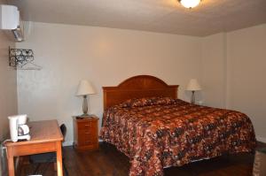 1 dormitorio con 1 cama y 1 mesa con 2 lámparas en Allen Street Inn, en Tombstone