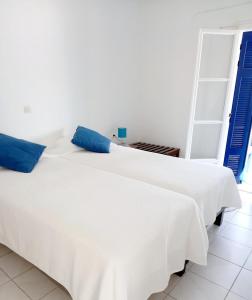 ein weißes Bett mit blauen Kissen in einem Zimmer in der Unterkunft Katys Apartement Fiskardo in Fiskardo