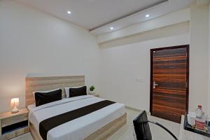 Schlafzimmer mit einem großen Bett mit einem Kopfteil aus Holz in der Unterkunft OYO Hotel Sunrise in Noida
