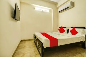 um quarto com uma cama com almofadas vermelhas e uma televisão em OYO ROYAL HAVEN em Hyderabad