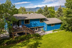 una casa azul con terraza y montañas al fondo en Mountain Escape: with Sauna near Yellowstone, en Bozeman