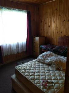 Schlafzimmer mit einem Bett und einem Fenster in der Unterkunft Casa in Quellón