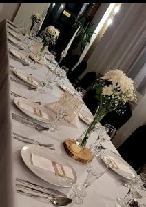 une longue table blanche avec des assiettes et des vases avec des fleurs dans l'établissement Hotel Kasieńka, à Hrubieszów