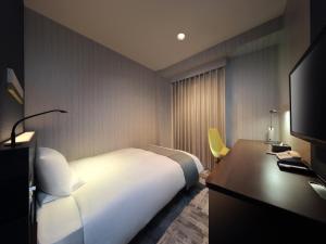 Dormitorio con cama, escritorio y TV en JR-East Hotel Mets Fukushima, en Fukushima