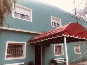 een blauw gebouw met een rode paraplu ervoor bij Hotel Embassy in Miramar