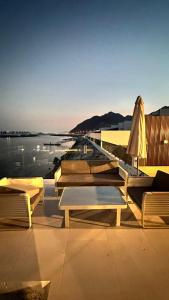 Luxury Villa 5 bedrooms with sea view and free boat في الفجيرة: مجموعة طاولات وكراسي بجانب جسم ماء