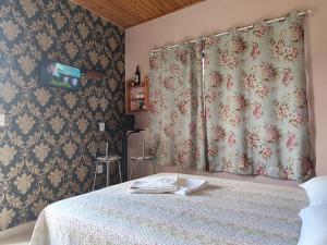 1 dormitorio con 1 cama con cortina y TV en Pousada Estrela Do Luar, en Urubici