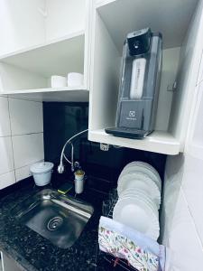 a kitchen with a sink and a microwave on a shelf at Beira Mar Copa in Rio de Janeiro