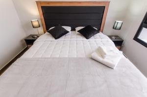 a large white bed with black pillows in a bedroom at Delightful Apt Two Minutes Away From La Galeria in Asuncion