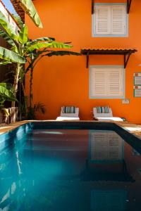 una piscina frente a una casa con una pared de color naranja en Vila Charme en Jericoacoara