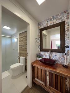 a bathroom with a sink and a toilet and a mirror at Apartamentos de Altitude Urubici in Urubici