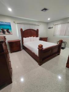 a bedroom with a large wooden bed with white sheets at Riverside Retreat: Deck Bar, FirePit, Boat Parking in Fort Myers