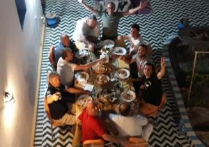 een groep mensen die rond een tafel zitten met borden eten bij Casa laman in Merzouga