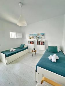 a white bedroom with two beds and a book shelf at La dolce vita in Mala
