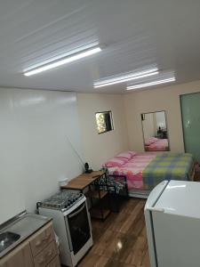 a room with a bed and a kitchen with a stove at Casa de Hóspedes Stulert in Blumenau