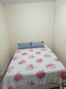 um quarto com uma cama com flores cor-de-rosa em Casa de Hóspedes Stulert em Blumenau
