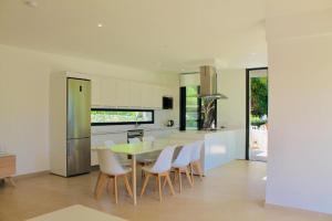 a kitchen with a dining table and white chairs at Villa SONIA in Cala en Blanes