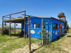 a blue tiny house in a field near the ocean at Casita de Mar in Cabo Polonio