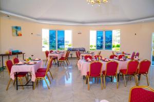una sala da pranzo con tavoli, sedie e finestre di Calfie Resort Kisumu a Ahero