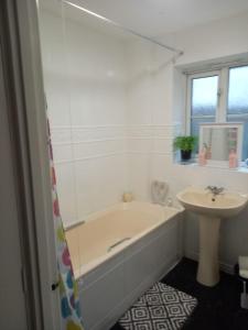 a white bathroom with a tub and a sink at Cozy House, Garden, Free Parking, Opposite Train station with Disneyplus & Netflix included in West Thurrock
