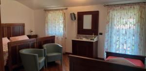 Tavagnacco的住宿－托努蒂農家樂，一间卧室配有一张床、两把椅子和镜子