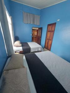 a bedroom with two beds and a blue wall at Sleeping Mountain Arenal in Fortuna