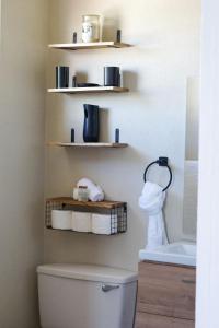 a bathroom with a toilet and shelves on the wall at Green Door Oasis in Christ Church