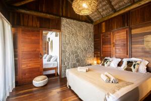 a bedroom with a large bed with a stone wall at Rancho Noé Cumbuco in Caucaia