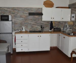 a kitchen with white cabinets and a brick wall at Siesta B&B Vryheid in Vryheid