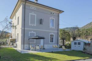 una casa bianca con tavolo e sedie in cortile di [*ViLLA GiUSTi LiBERTY HOME*] SPA BBQ Wifi Parking a Lucca