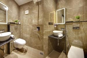 a bathroom with two sinks and a toilet and a shower at BLESS INN - Near Connaugt Place in New Delhi