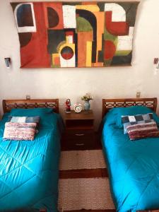 2 camas en una habitación con un cuadro en la pared en Alojamiento en Casona Bellavista, una experiencia Patrimonial-Natural, en Talca