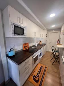 a kitchen with white cabinets and a microwave at Apartamento Bolingas in Comillas