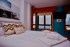 Schlafzimmer mit einem großen weißen Bett und einem Fenster in der Unterkunft Centro, playa y puesta de sol in A Coruña