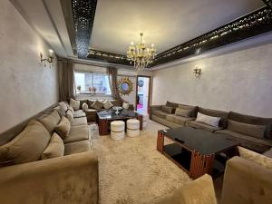 un grand salon avec des canapés et un lustre dans l'établissement Ibtissam home, à Kenitra
