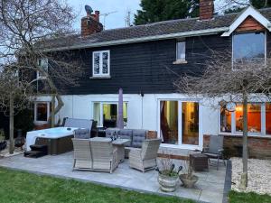 un patio con sillas y una bañera frente a una casa en Brook Farm, en Ringwood