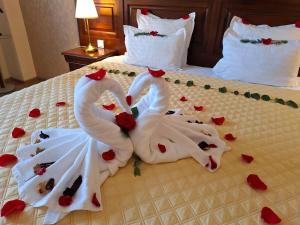 dwa łabędzie zrobione z róż na łóżku w obiekcie Grand Hotel Sofianu w mieście Râmnicu Vâlcea