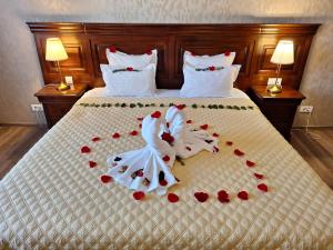 Una cama con dos toallas de boda y rosas rojas. en Grand Hotel Sofianu en Râmnicu Vâlcea