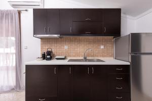 La cuisine est équipée de placards noirs et d'un réfrigérateur en acier inoxydable. dans l'établissement HOME WITH VIEW, à Xánthi