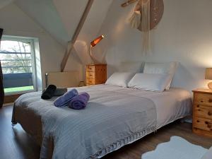 una camera da letto con un letto e asciugamani viola di La maison au cœur de la forêt a Rosporden