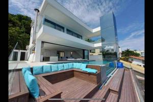 a large white house with a blue couch on a deck at Mansão com vista cinematográfica pro mar! in Guarujá