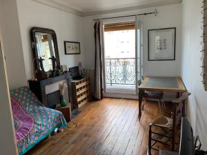 a room with a desk and a table and a window at Stylish Flat with Balcony Facing South in Paris