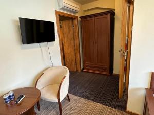 a hotel room with a chair and a table and a television at GLORIETTA Apartments & SPA in Iwonicz-Zdrój