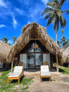 a resort with two chairs and a straw hut at Hotel Isla Mucura in Isla Mucura